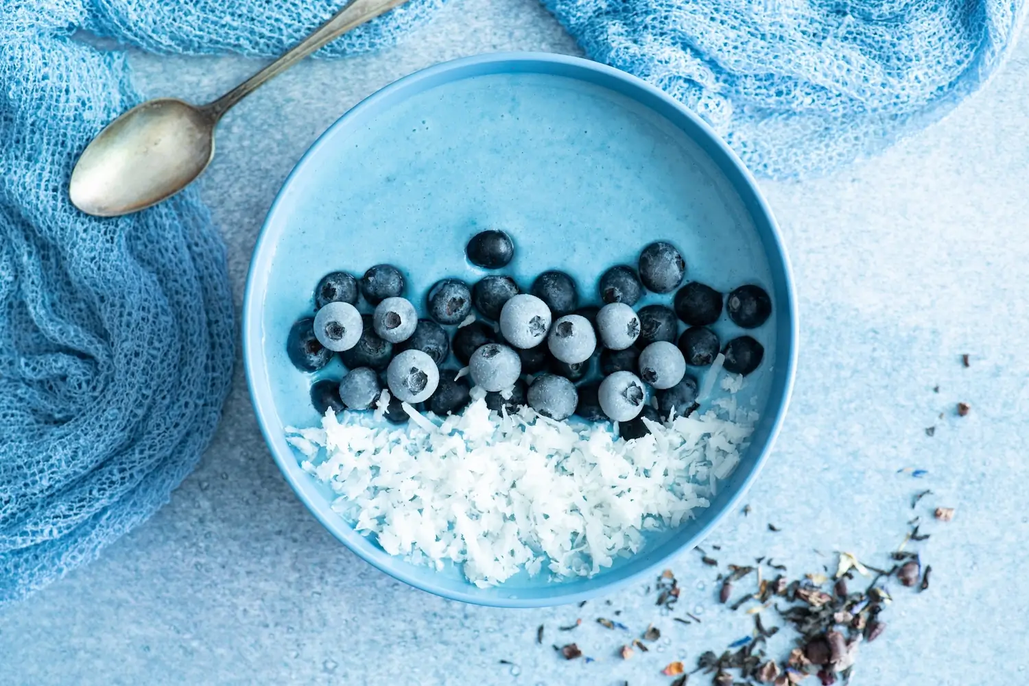 Blauwe gezonde smoothie bowl met bosbossen en kokos als foto voor op de achterwand van de keuken